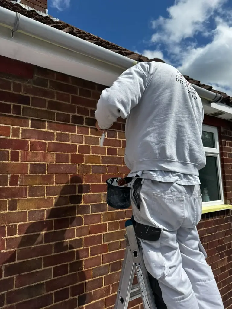 Archers decorator painting fascias from a ladder